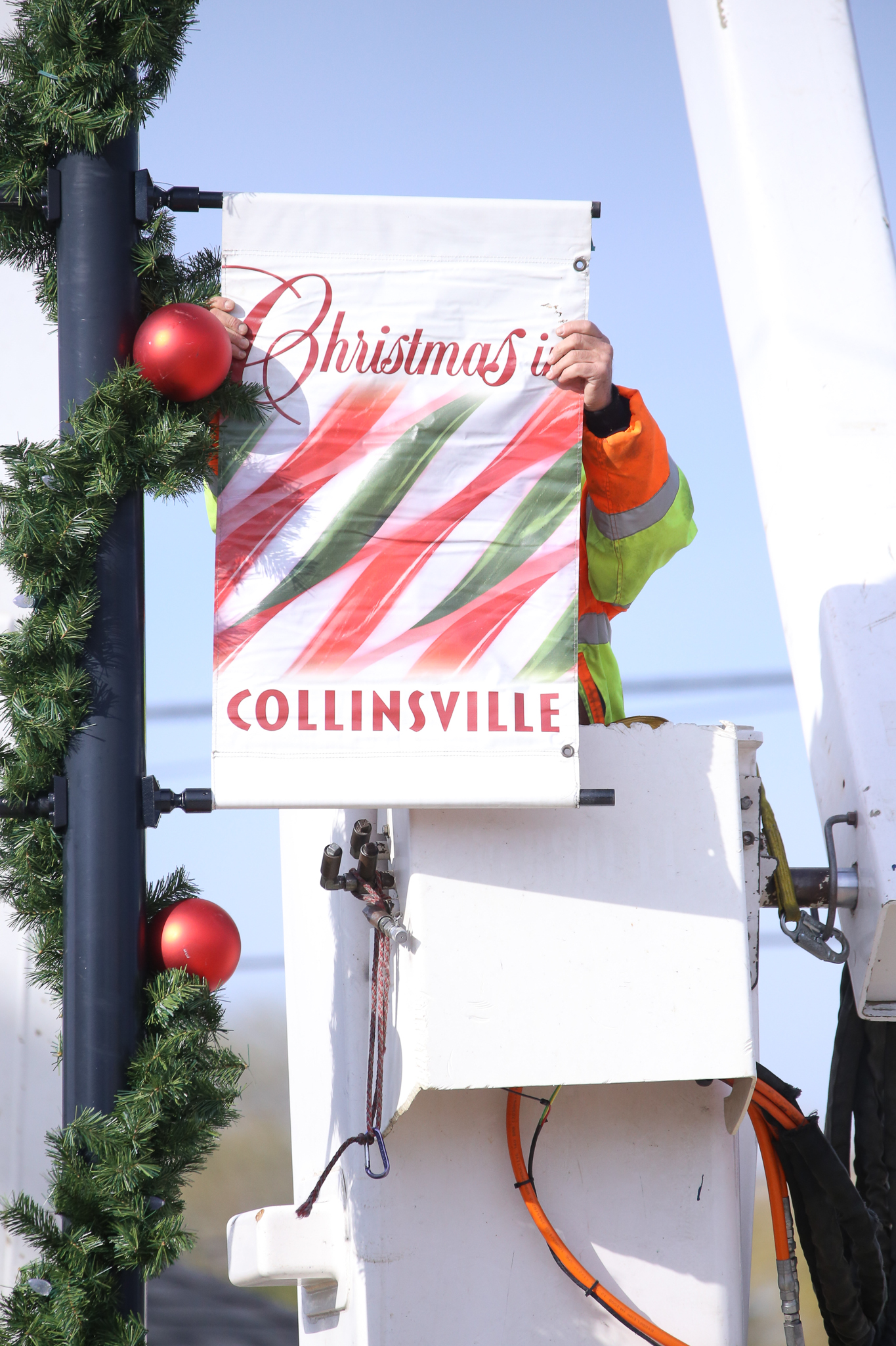 A city worker installs a "Christmas in Collinsvile" banner Monday, Nov. 21, 2016 on Main St. (Photograph by Brian Munoz / The Collinsville Chronicle)